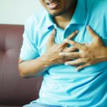 A close-up image of a man clutching his chest, indicating heart pain or discomfort.