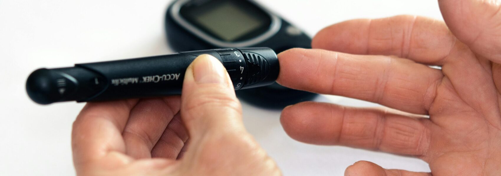 Close-up image of a person using a glucometer for diabetes management indoors.
